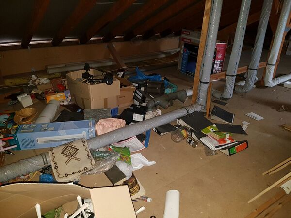 Dachboden mit Rohrleitungen, Kartons, Aktenordnern und verschiedenen Gegenständen voller Unordnung.