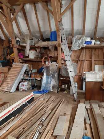 Dachboden mit Holzlatten, Baumaterialien, Werkzeugen und Leiter für Renovierung.