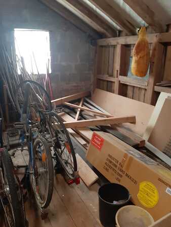 Abstellraum mit alten Fahrrädern, Holzlatten, Karton und Schinken an Holzbalken.