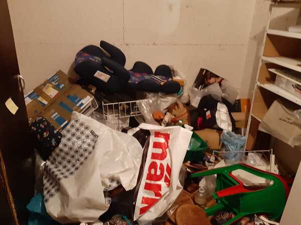 Unordentlicher Abstellraum mit Kartons, Tüten, Regalen und verschiedenen Haushaltsgegenständen.